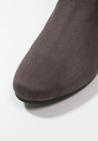 Botín gris de ante hasta el tobillo con punta afilada y superficie texturizada, que presenta una suela plana negra y un diseño sin costuras.
