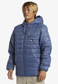 Gepolsterte blaue Daunenjacke aus glänzendem Material, mit Kapuze, Reißverschluss vorn und einer Brusttasche mit Logo. Texturiertes Designdetail.