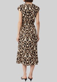 Midikleid mit einem schwarz, creme und orange gemusterten Design, elastischem Bund, kurzen Ärmeln und einer lockeren Silhouette mit fließendem Textil.