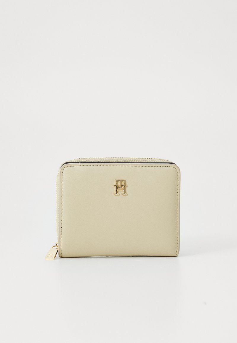 Beige leather wallet with a zippered closure, featuring a gold logo accent on the front, rectangular shape, and smooth texture.