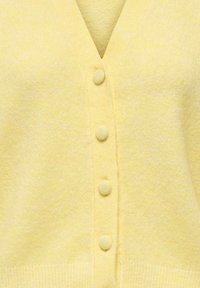 Myk gul strikket cardigan med matchende knapper trukket i stoff og V-hals design.