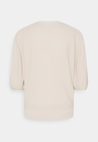 Jersey de punto color beige claro con corte relajado, manga corta y dobladillo acanalado, fabricado en un material suave y texturizado.