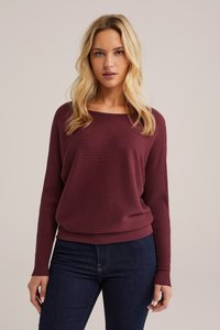 Bordo raštuota ilgaaukštė megztinis su laisvu kirpimu ir plačia iškirpte, derinamas su tamsiomis džinsomis. Minkšta tekstūra su subtiliu raštu.