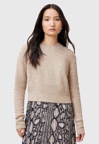 Maglione beige in maglia con scollatura rotonda, bordo a coste e maniche lunghe, abbinato a una gonna a righe in bianco e nero. Dettaglio del tessuto texture.