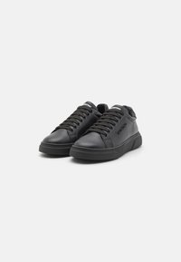 Baskets en cuir noir avec un design basse, bout arrondi, fermeture lacée à l'avant, col rembourré et semelle texturée avec une marque sur le côté.