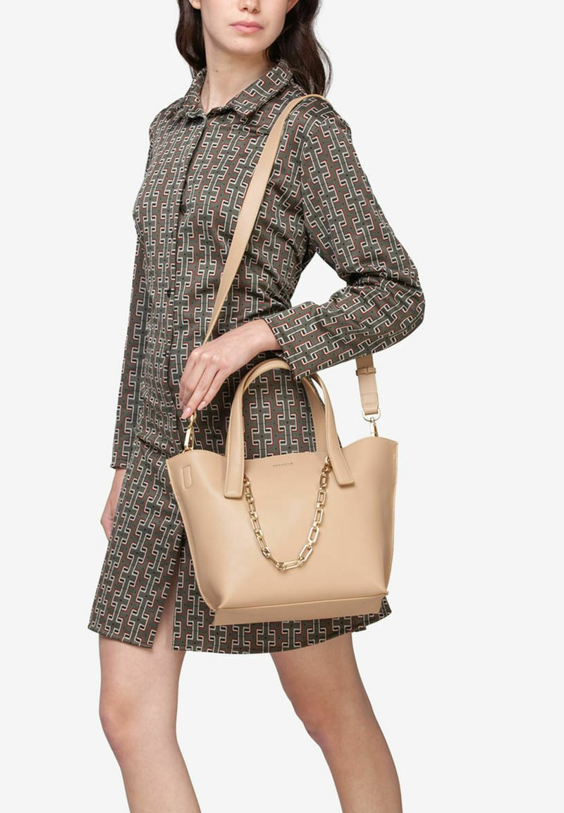 Beige læderhåndtaske med dobbelte top håndtag og en aftagelig rem. Har en guldkædeakcent og en struktureret, rektangulær form.