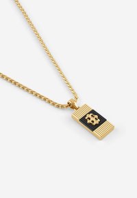 Ketting met goudkleurige tint en een rechthoekige hanger met zwarte, textuurrijke strepen en een centraal, sierlijk ontwerp. De ketting heeft een gedraaid patroon.