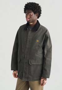 Σκούρο πράσινο μπουφάν από καμβά με γιακά από κορδόνι, δύο μεγάλες μπροστινές τσέπες και ένα μικρό λογότυπο. Χαλαρή εφαρμογή με κούμπωμα σε κουμπιά πατιλέτα.