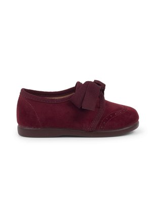 Scarpa in suede bordeaux con punta arrotondata, suola in gomma e fiocco decorativo sul davanti. Caratterizzata da cuciture tonali e una morbida fodera interna.