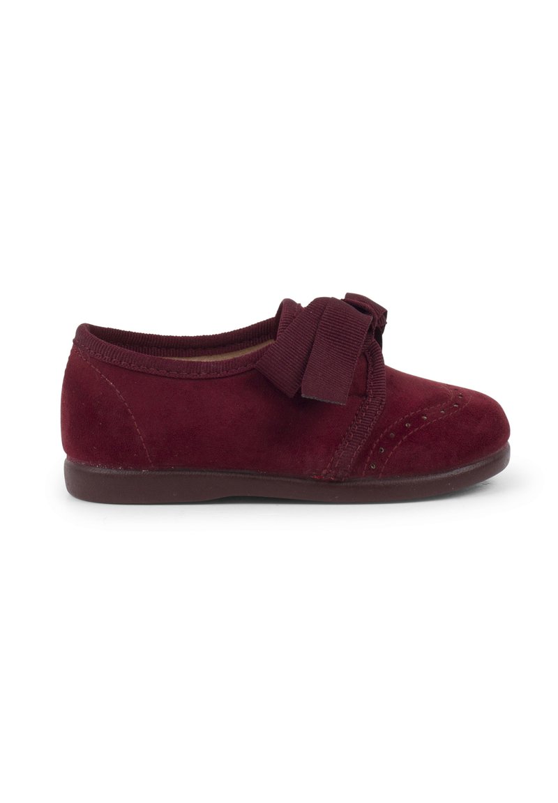 Scarpa in suede bordeaux con punta arrotondata, suola in gomma e fiocco decorativo sul davanti. Caratterizzata da cuciture tonali e una morbida fodera interna.
