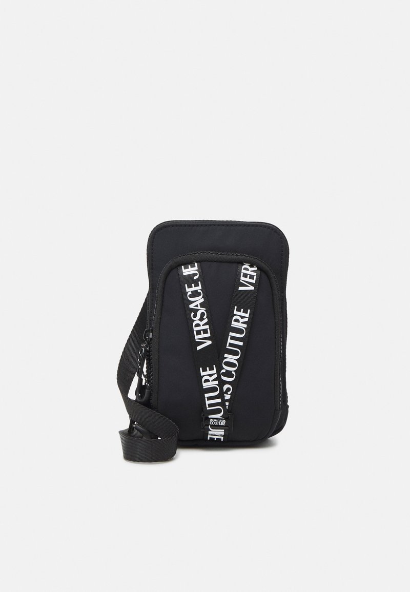 Kompakt sort crossbody-taske med hvide "Versace Jeans Couture" logo-stropper og en justerbar skulderrem.