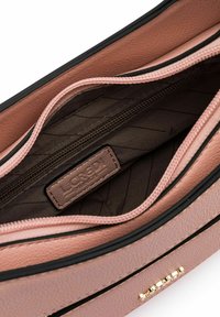 Interno di una borsa a tracolla in pelle rosa testurizzata con fodera marrone scuro, dotato di una tasca con zip e un'etichetta del marchio. Accenti in metallo dorato.