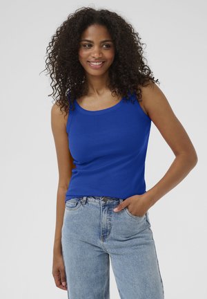 Blue cotton tank top with a scoop neckline and narrow straps, paired with light-wash denim jeans, featuring a classic fit and pockets.