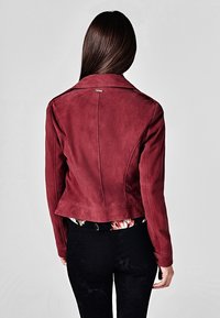 Bordeaux ruskindsjakke med en tætsiddende pasform, notch-krave og taljelængde. Har dekorativ syning og minimale hardware-detaljer.