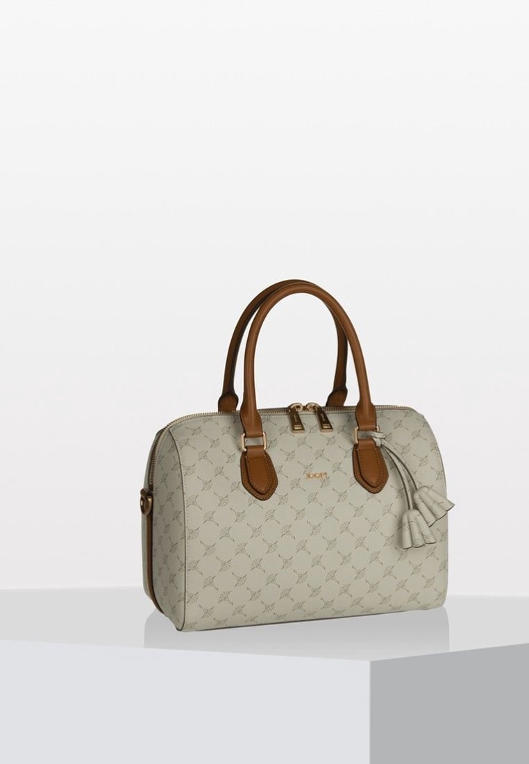 Beżowa torebka z teksturowanym wzorem, brązowymi skórzanymi elementami, podwójnymi uchwytami i zamkiem błyskawicznym. Z dwoma ozdobnymi chwostami.