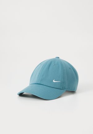 Teal baseball cap made of fabric with a curved brim. Features a white Nike logo on the front and six ventilation eyelets on top.