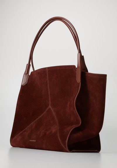 Καφέ σουέτ τσάντα tote με λείες δερμάτινες λεπτομέρειες, επιμηκυσμένους ιμάντες και κυματιστό σχέδιο. Διαθέτει δομημένη βάση και διακριτική λεπτομέρεια λογότυπου.