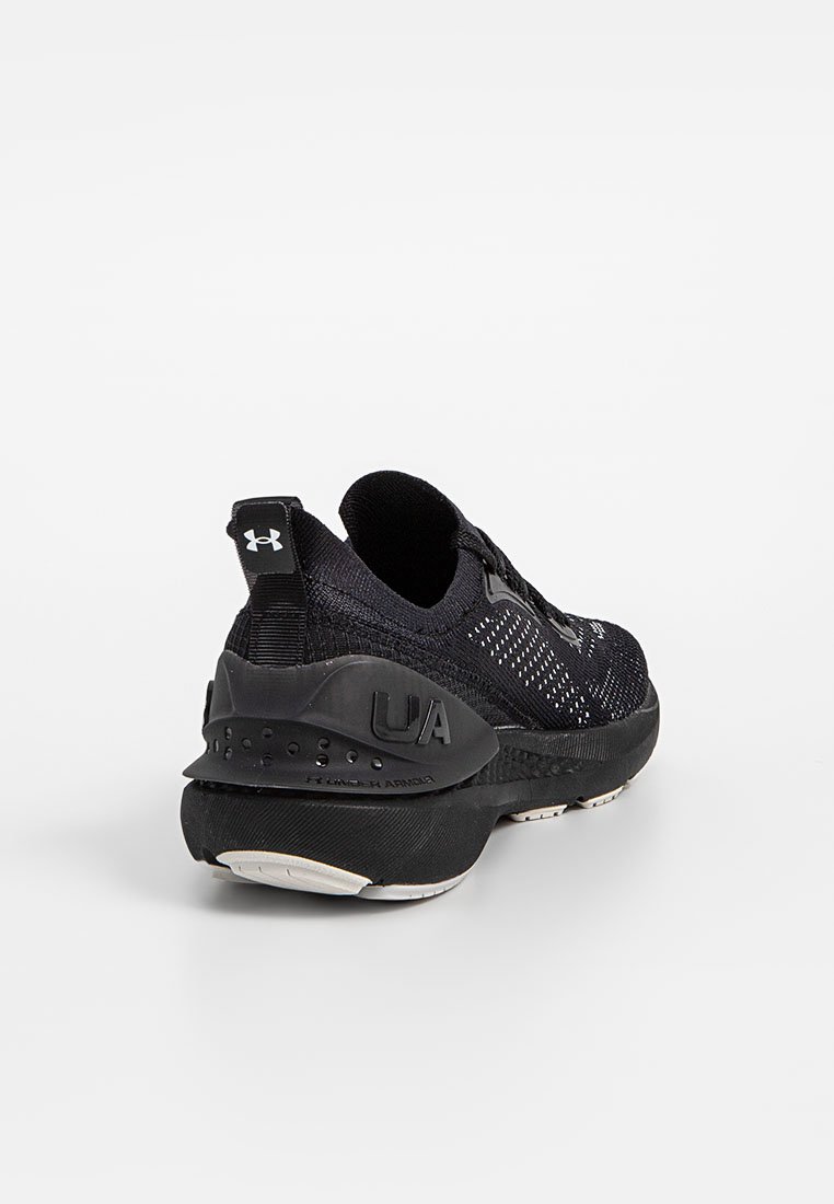 Zapatilla deportiva negra con parte superior de tejido texturizado, talón acolchado y suela de goma. Presenta un logo trasero y un diseño transpirable.