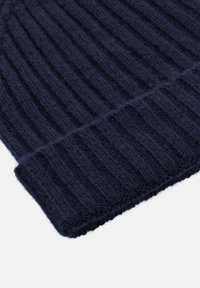 Morska modra rebrasta pletena kapa, mehka tekstura, zavihan rob, izdelana iz volne ali podobnega materiala, enotno šivanje, brez vidnih vzorcev ali dodatkov.