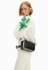 Borsa a tracolla compatta in pelle nera con accenti bianchi, design goffrato, tracolla regolabile e hardware metallico. Dettagli floreali verdi ricamati sulla parte superiore.