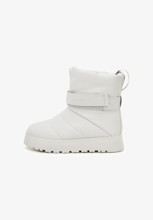 Białe, wyłożone pianką botki za kostkę o gładkiej skórzanej powierzchni, z elastycznym paskiem i grubą, teksturowaną gumową podeszwą. Posiadają pętelkę ułatwiającą zakładanie.