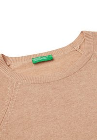 Jasno beżowy sweter dziany z okrągłym dekoltem, prążkowanym kołnierzem i zieloną metką z napisem "UNITED COLORS OF BENETTON" wewnątrz.