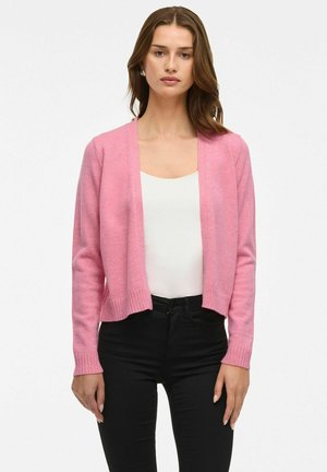 Pink cropped cardigan with long sleeves and ribbed cuffs, made of soft material. Worn over a white top and paired with black pants.