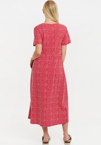 Abito midi rosso a fiori con maniche corte, vestibilità comoda e vita arricciata. Presenta un piccolo motivo a pois bianchi. Tessuto dalla texture liscia.