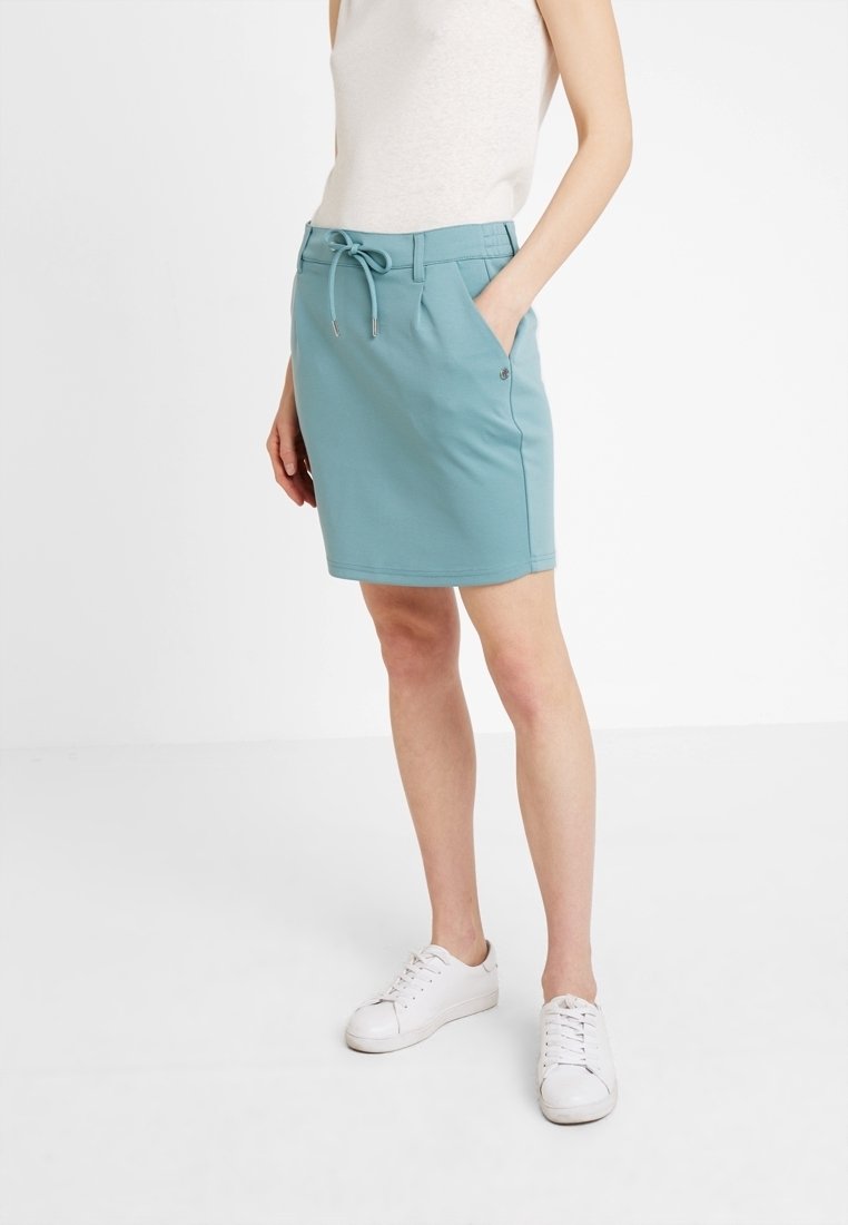 Spódnica do kolan w kolorze morskim, wykonana z miękkiego, elastycznego materiału, z wiązanym w pasie sznurkiem, z dwoma bocznymi kieszeniami i gładką fakturą.