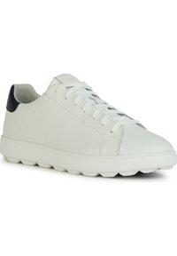 Valkoinen nahkainen lenkkikenkä, jossa on sileä pinta, nauhakiristyksellä ja kontrastivärinen tummansininen kantapääkoristus. Pyöreä pohja, jossa on erottuvat nappulat.