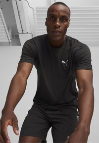 Juodas sportinis marškinėliai ir šortai, pagaminti iš lengvo, drėgmę sugeriančio audinio. Marškinėliai turi mažą baltą Puma logotipą.