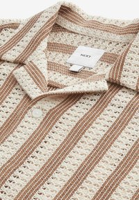 Kremowo-brązowa dzianinowa koszulka polo w paski o teksturowanym, otwartym splocie, z zapięciem na guziki i białą metką z napisem "NEXT".