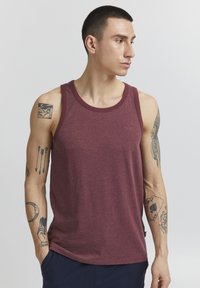 Bordeauxfarbener ärmelloser Tanktop mit rundem Ausschnitt, gefertigt aus einem weichen, strukturierten Stoff. Mit kleinem gesticktem Logo auf der Brust.