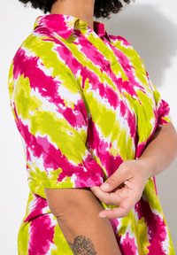 Kortärmad skjorta med ett livfullt rosa och grönt tie-dye-mönster. Tillverkad av bomull, har den en avslappnad passform och en krage med knappdetaljer.