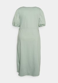 Vestido verde pálido, até ao joelho, com mangas bufantes, gola redonda e uma cintura ajustada. Tecido suave, ligeiramente texturizado e sem padrões.