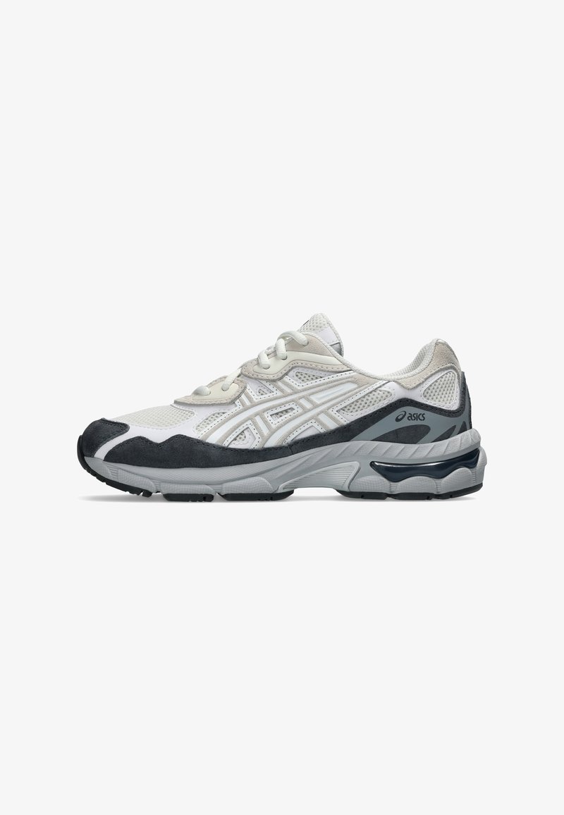 Baskets de sport Asics blanches et noires avec tige en mesh, superpositions en daim et semelle épaisse rembourrée, présentées de côté sur fond blanc.
