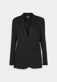Blazer noir sur mesure avec un motif monogramme subtil, revers crantés, deux boutons sur le devant et deux poches passepoilées, présenté sur fond blanc.