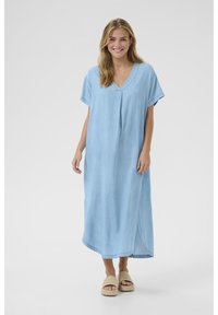 Šviesiai mėlynas džinsinis suknelė su V formos iškirpte, trumpomis rankovėmis ir šoninėmis prasmėmis. Lengvas audinys turi švelnią tekstūrą, siekiančią iki vidurio blauzdų.