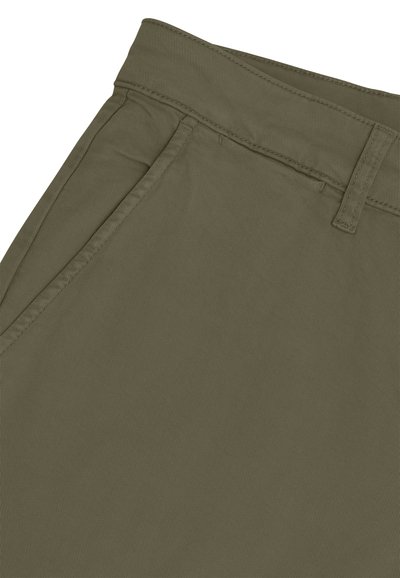 Gros plan sur un pantalon vert olive montrant la ceinture, les passants de ceinture et une poche latérale inclinée avec des coutures détaillées.