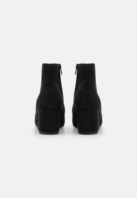 Black suede ankle boots with a rounded toe, side zippers, and a chunky heel. Smooth texture and simple design with no visible patterns.
