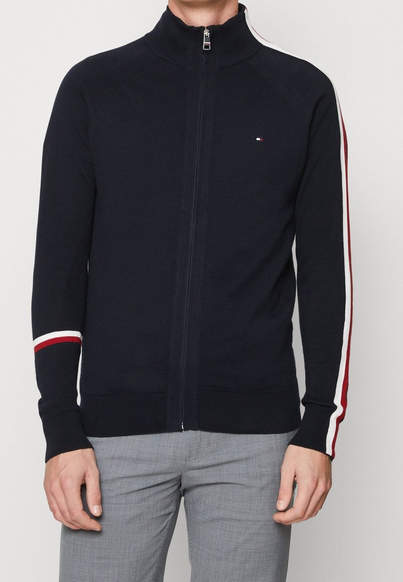 Cardigan zip-up da marina realizzato in materiale lavorato a maglia, con dettagli a strisce bianche e rosse sulle maniche e polsini testurizzati.