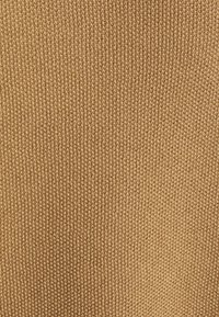 Tissu tricoté brun avec un motif texturé et légèrement en relief ; des coutures régulièrement espacées créent une apparence structurée dans l'ensemble.