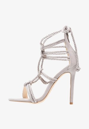 Grijze suède sandalen met hoge hakken en een gestructureerd ontwerp, voorzien van gedraaide touwaccenten en een open teen. De stiletto hiel voegt hoogte en elegantie toe.