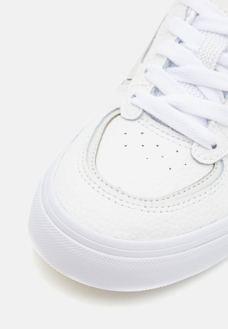 Białe skórzane sneakersy o fakturowanej powierzchni, zaokrąglonym nosku i białych sznurówkach. Posiadają małe perforacje oraz białą gumową podeszwę.