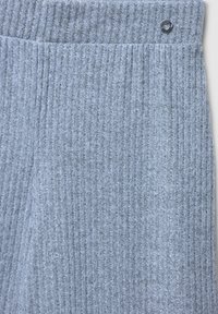 Szary ribbed materiał z teksturowanym wykończeniem, z zawiniętym pasem i małym, okrągłym detalem akcentującym w górnym rogu.