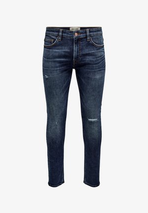 Jean en denim bleu foncé avec une coupe ajustée, présentant des effets de délavage subtils, un léger vieillissement et un design classique à cinq poches. Quincaillerie en cuivre.