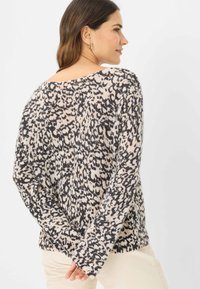 Strikket sweater med en løs pasform, der har et leopardprint i sort og beige. Lange ærmer, rund halsudskæring, blød tekstur.