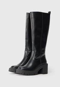 Black knee-high boots made of smooth leather, featuring a thick block heel and rubber sole with a textured pattern. Simple, no visible hardware.
