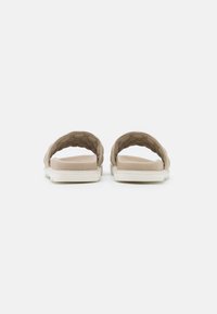 Sandales beiges à brides matelassées et semelles rembourrées, vues de face sur fond blanc.