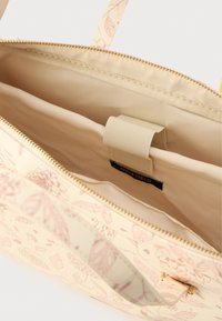 Beež värvi kandekott roosa lillemustriga. Lukuga ülaosa, kuldsed detailid ja sisetasku. Sile tekstuur, tugevdatud sangad.